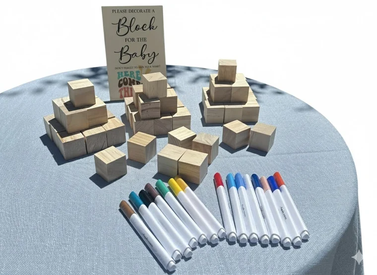 A baby shower activity table with wooden blocks, colored markers and a sign for guests.