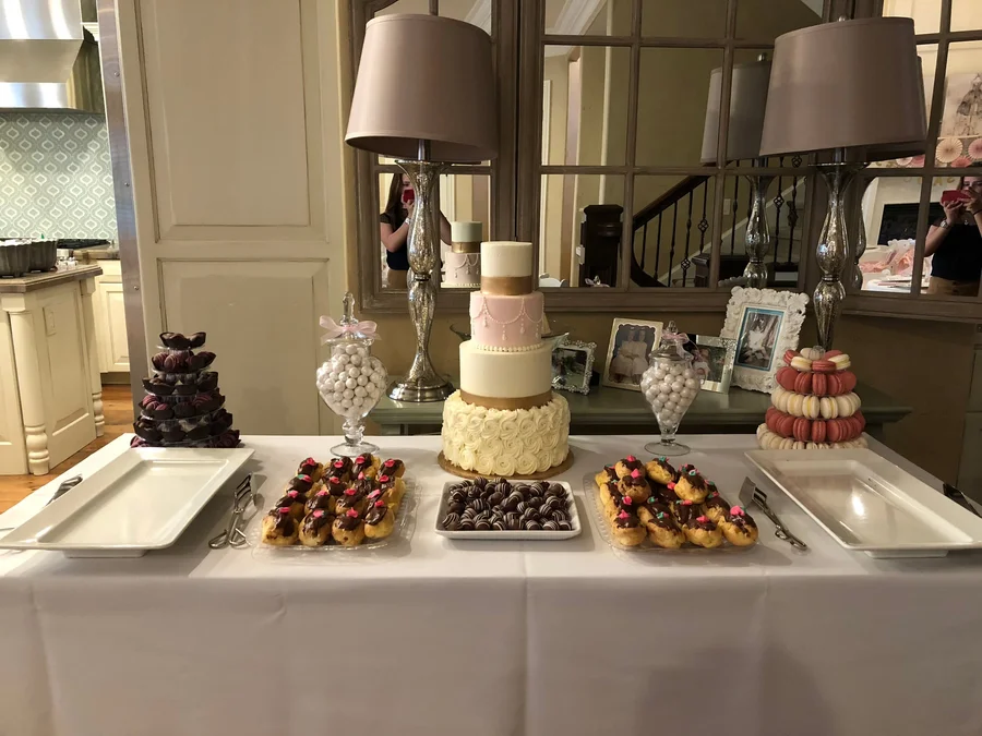 Dessert table with tiered cake, chocolate treats and small sweets in a home setting