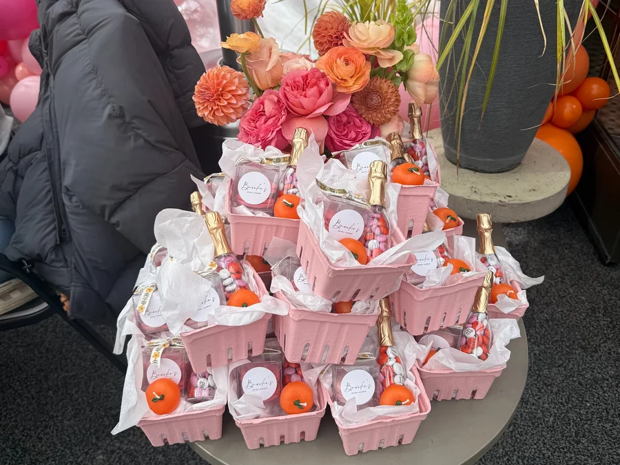 Pink gift boxes with orange fruit and flowers arranged on a display table