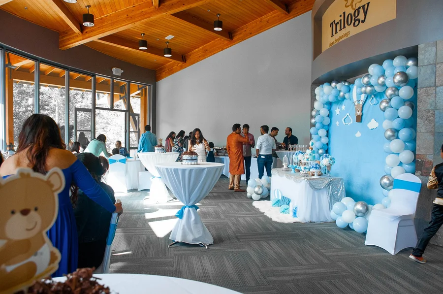 Baby shower venue with a blue balloon wall and guests mingling at tables