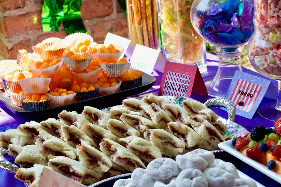 Colorful dessert buffet with pastries, candy jars and snacks on purple linens