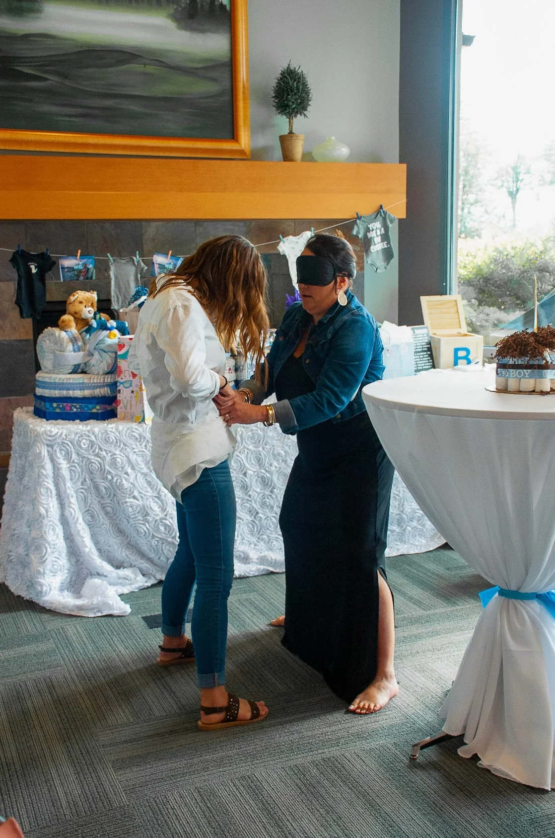 Guests mingling in a banquet room decorated with white linens and blue ribbon accents.