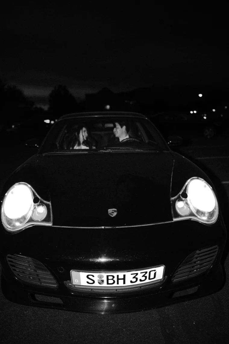 A black sports car with glowing headlights, photographed at night.