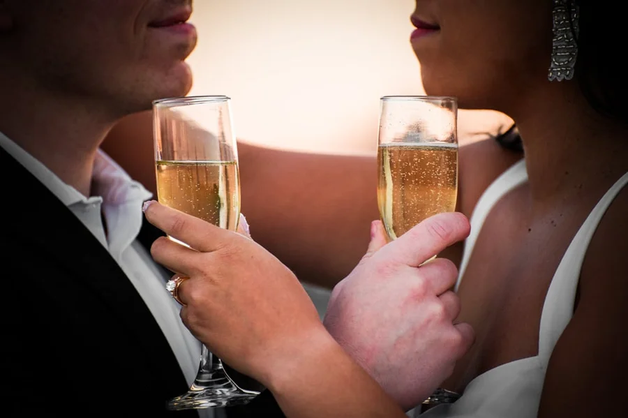 Couple toasting with champagne flutes during an engagement session at golden hour