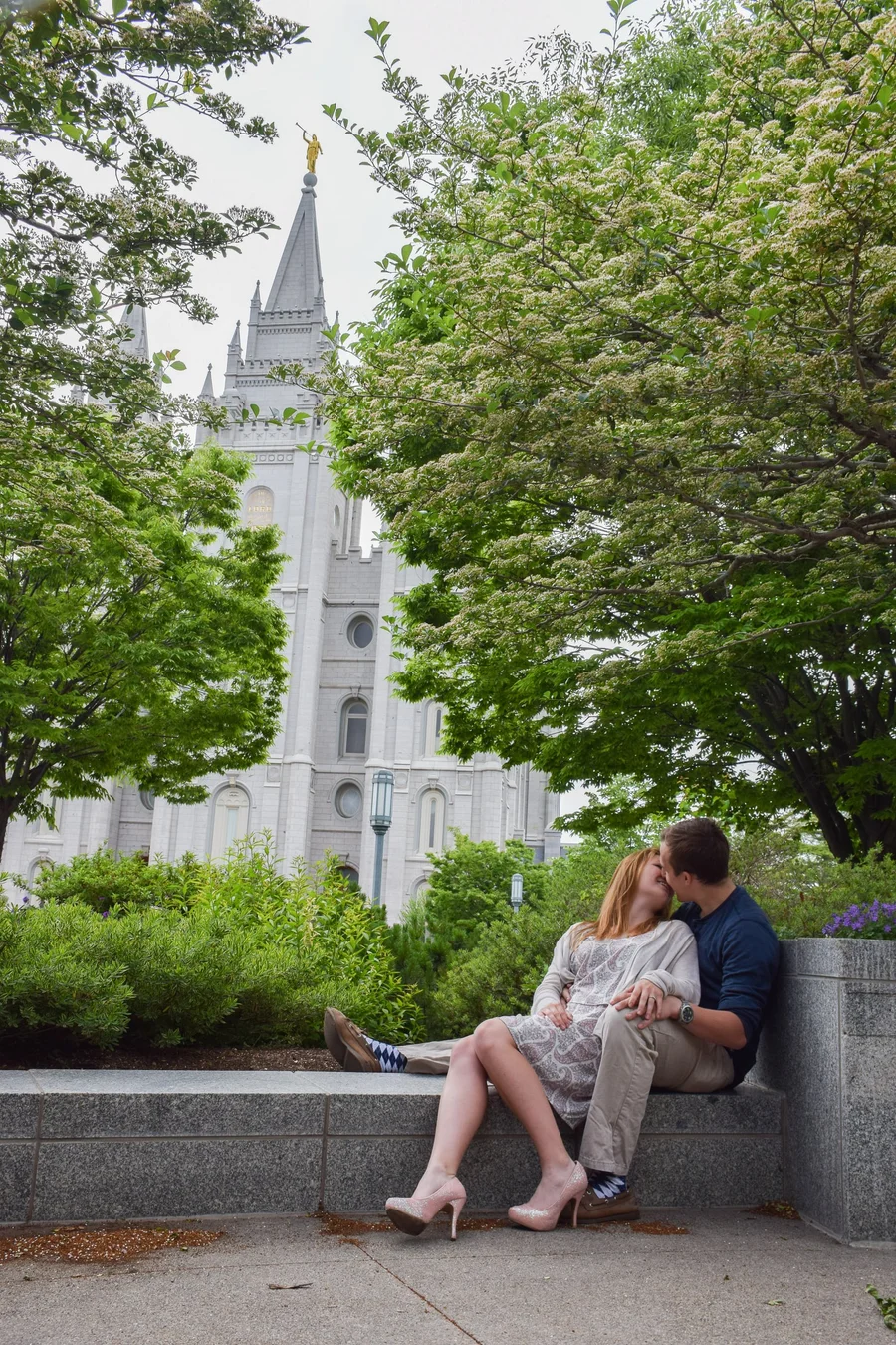 Couple sitting together on a stone ledge beside a historic temple with spires