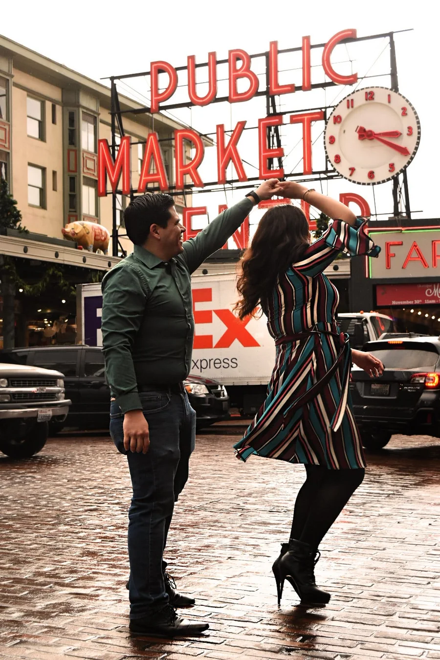 Couple posing playfully under the Public Market sign on a cobblestone street