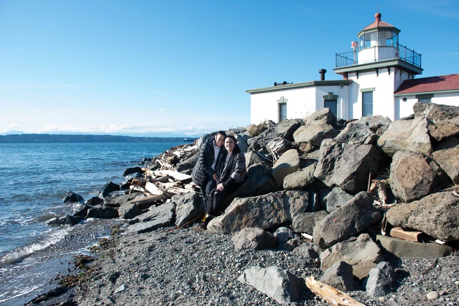 Rocky shoreline with a white lighthouse under a clear blue sky
