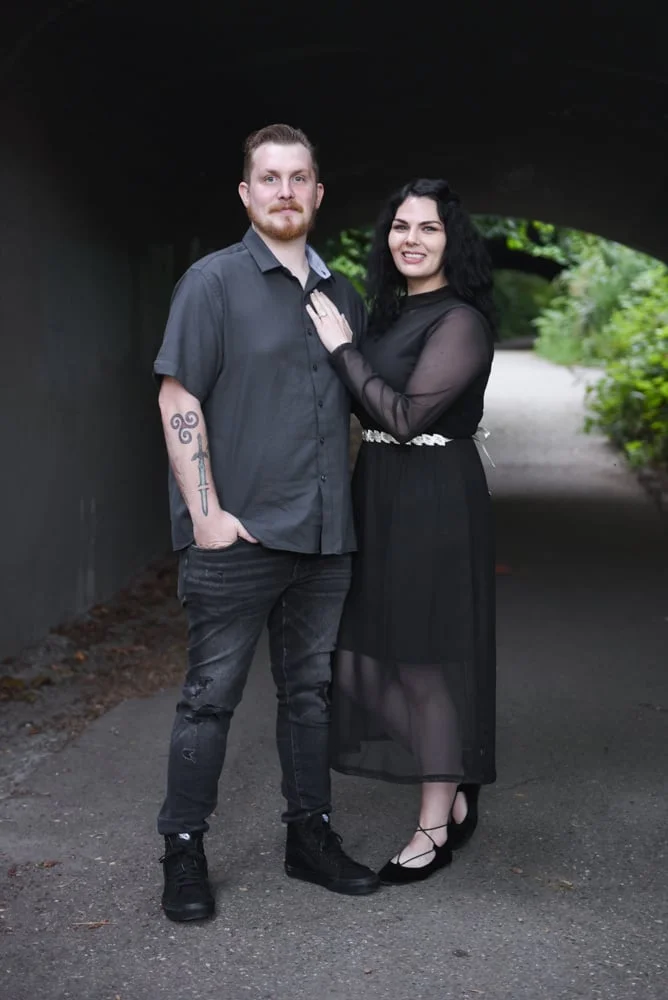 Tattooed couple standing hand in hand in a dark tunnel-like pathway