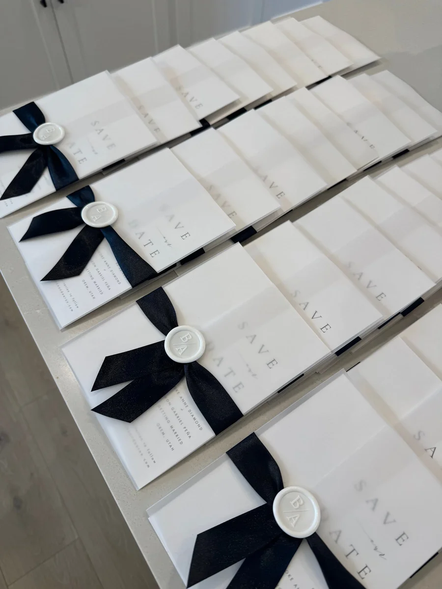White invitation suites tied with black ribbon and wax seals