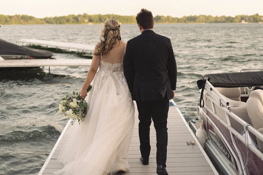 Bride and groom walking down a lake dock in the evening light