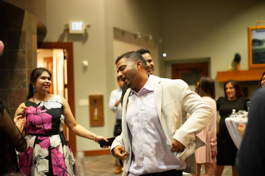 Smiling guests dancing and laughing at a reception in a lounge area