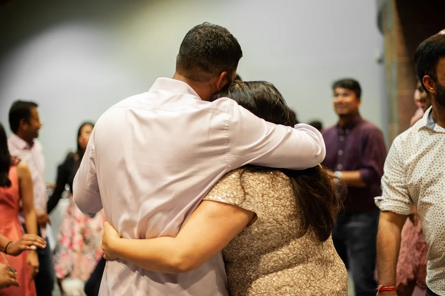 Wedding guests hugging warmly during an emotional moment at a reception