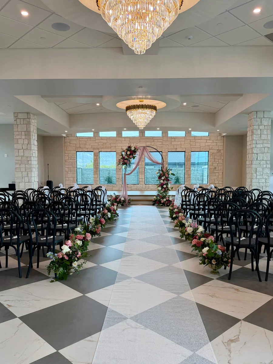 Checkerboard aisle and black chairs in an elegant ceremony hall with chandeliers