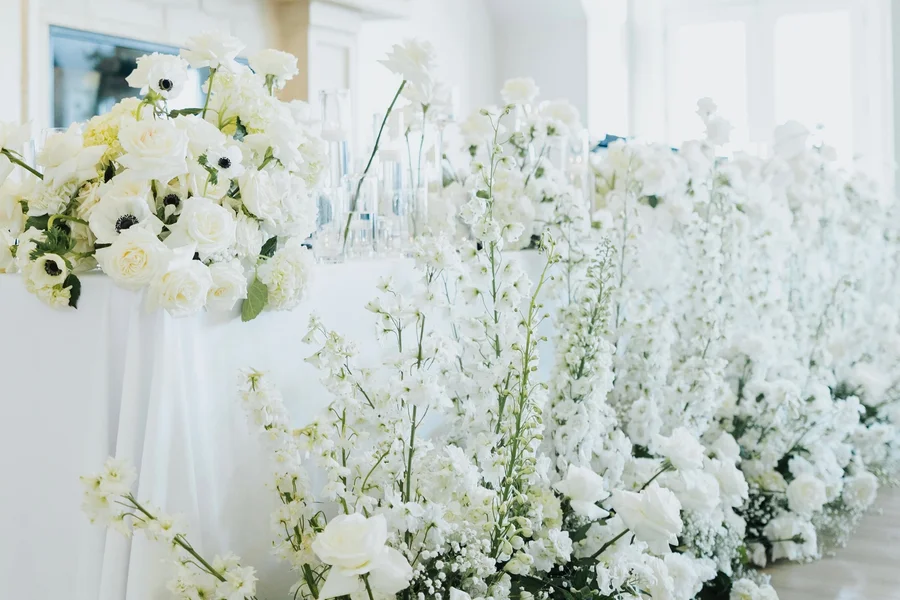 White floral arrangements and tall stems decorating a bright wedding venue