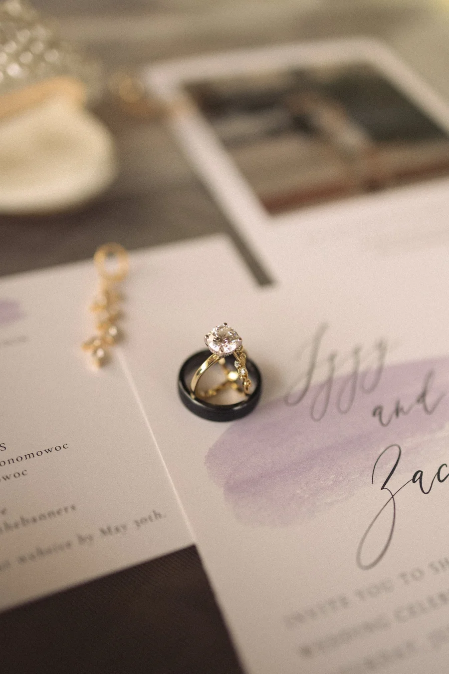 Wedding invitation suite with rings and jewelry laid out in a flat lay