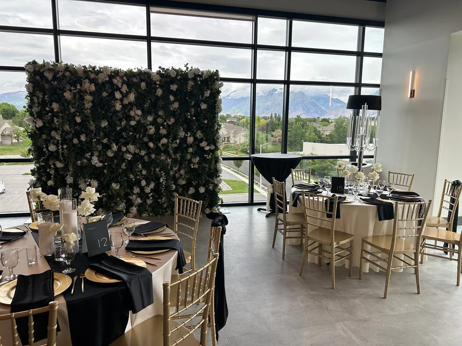 Reception room with a floral wall backdrop and tables set in black and gold
