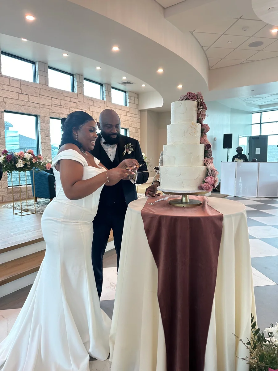 Bride and groom cutting a tiered white wedding cake at a venue