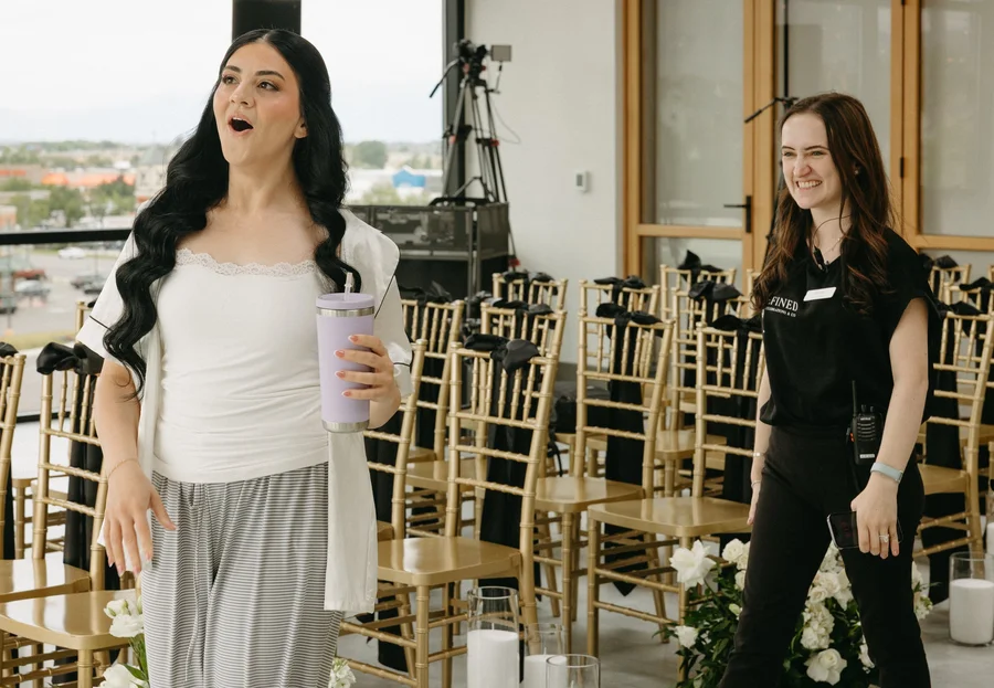 Excited woman and venue staff member smiling in a room with gold chairs