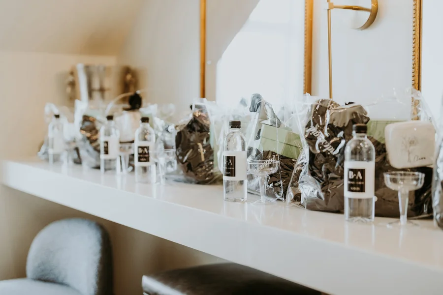 Small wedding favors and bottles arranged on a white shelf